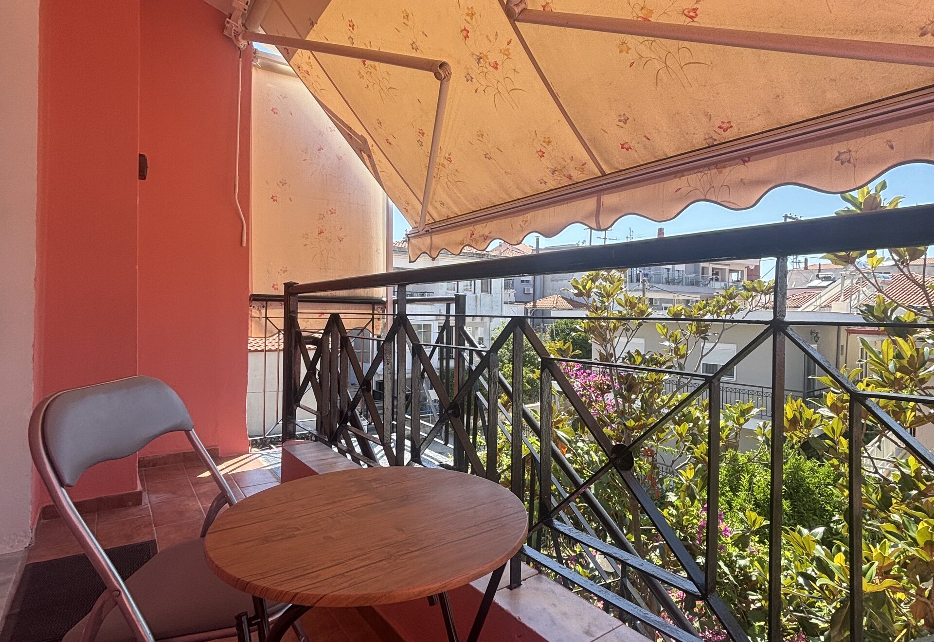 Polychrono Coral Two-Bedroom Apartment balcony with table, chairs, and awning shade