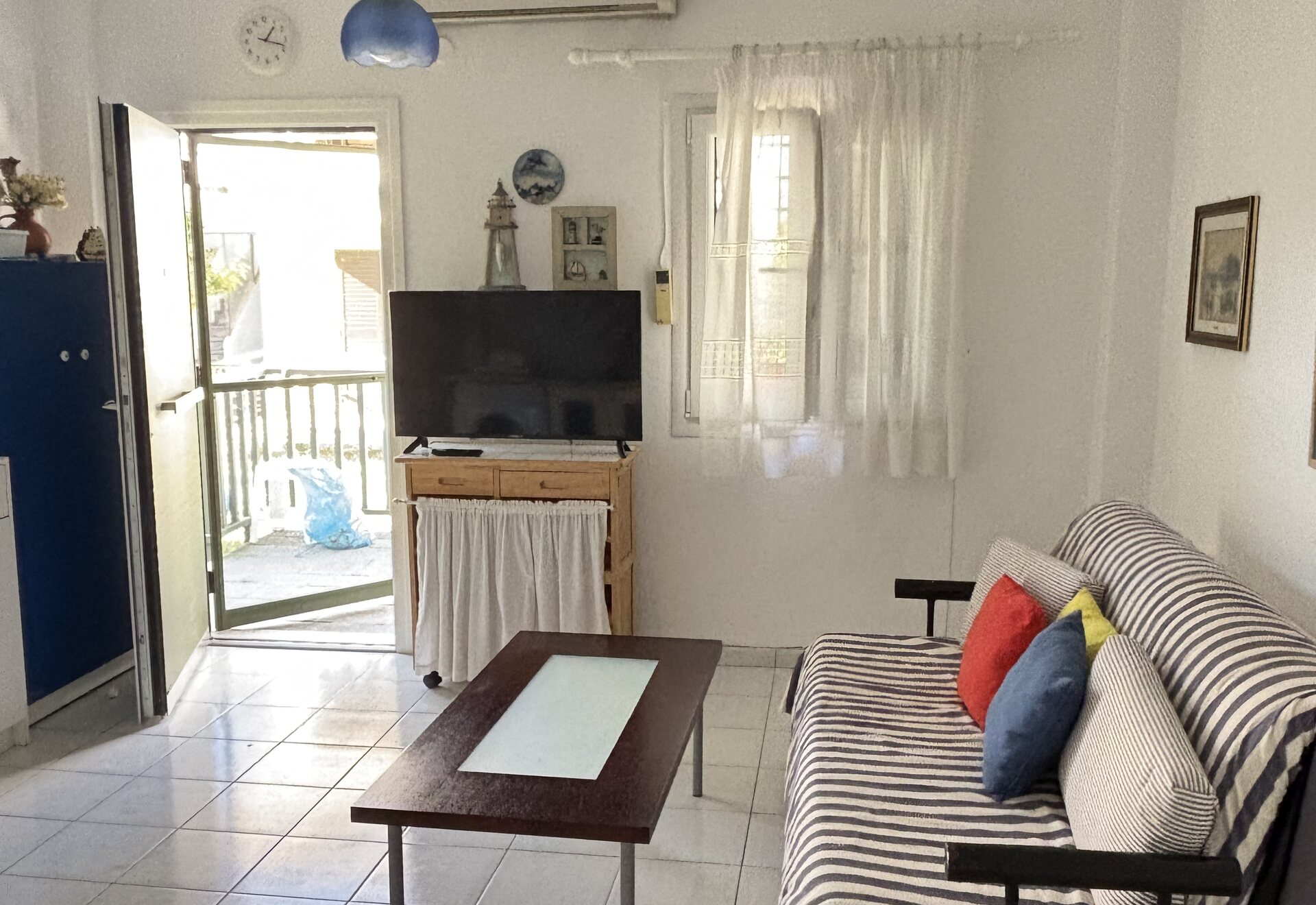 Polychrono Duplex living room with sofa, TV, and balcony door