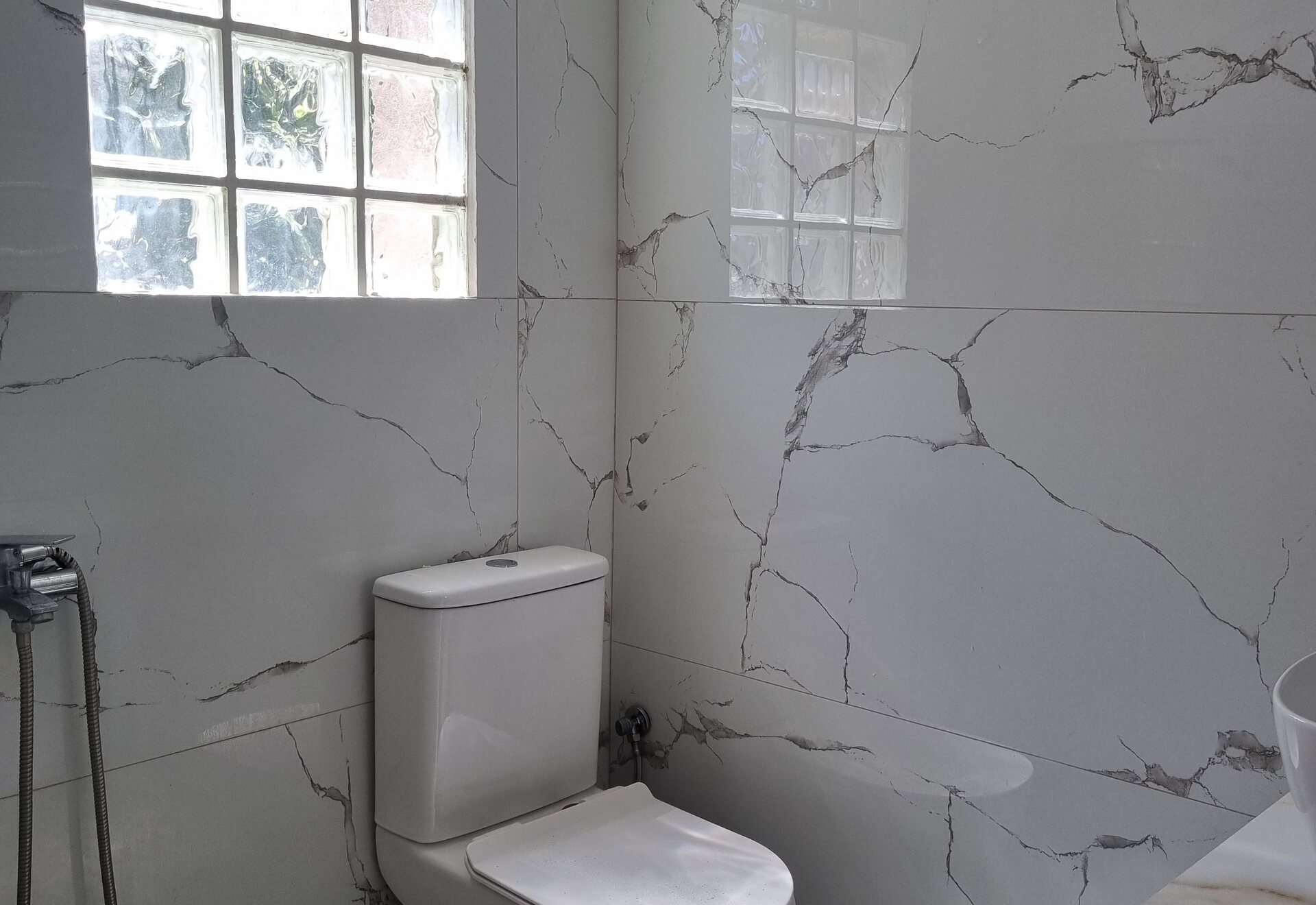 Polychrono Patio Retreat bathroom toilet, shower area, and glass-block window