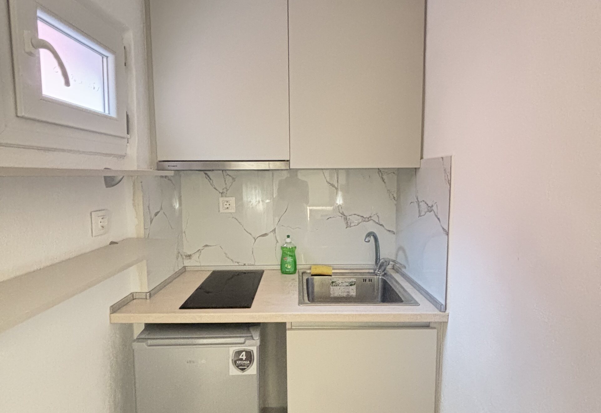 Polychrono Patio Retreat kitchenette with sink, stovetop, and compact refrigerator