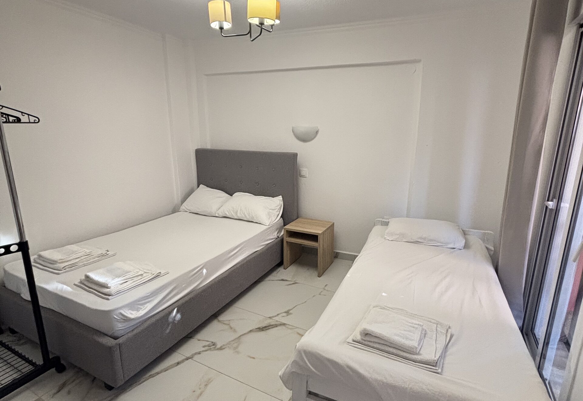 Polychrono Patio Retreat sleeping area with beds, wardrobe rack, and window