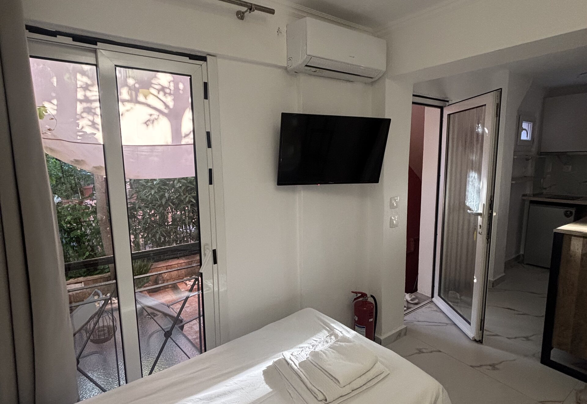 Polychrono Patio Retreat studio bed with TV, air conditioner, and patio door