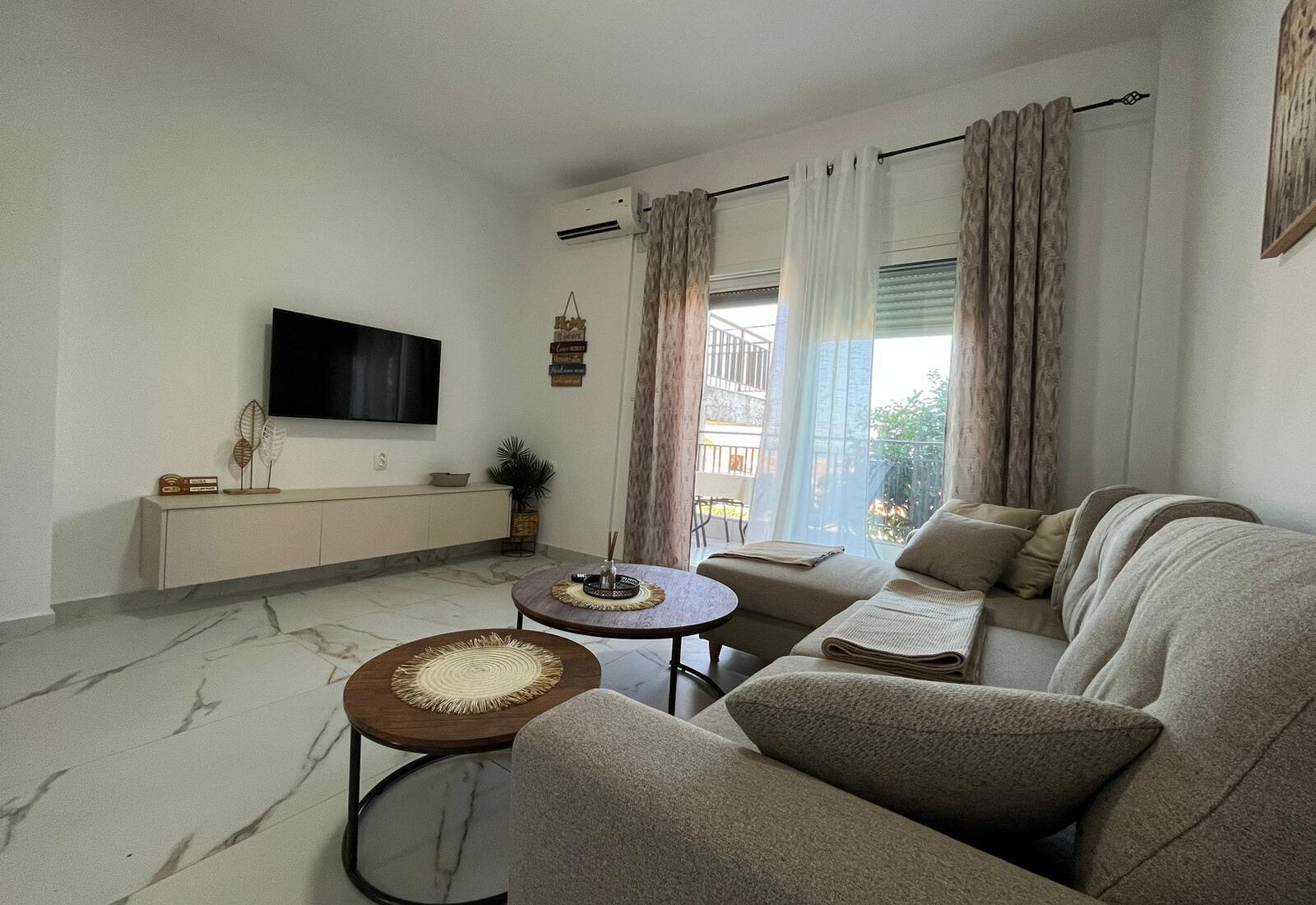 Aegean Dream living room with sofa, TV, and balcony doors